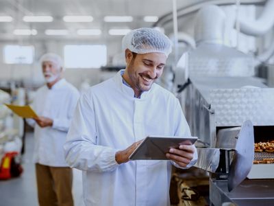 Supervisor de producción monitoreando indicadores de gestión diaria en tableta digital en planta de manufactura