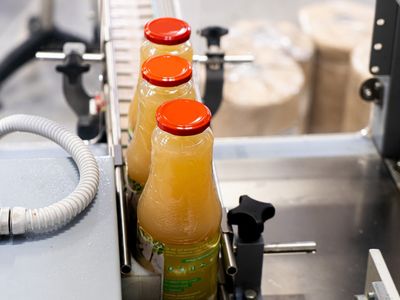 Botellas de jugo avanzando por transportador automatizado en línea de producción industrial