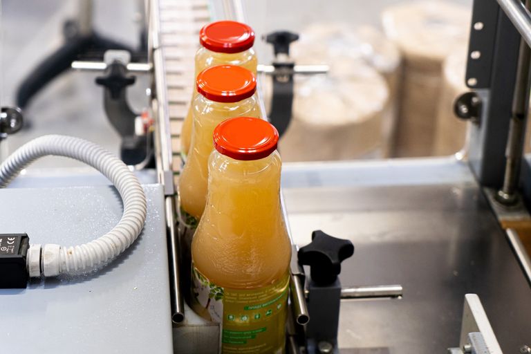 Botellas de jugo avanzando por transportador automatizado en línea de producción industrial